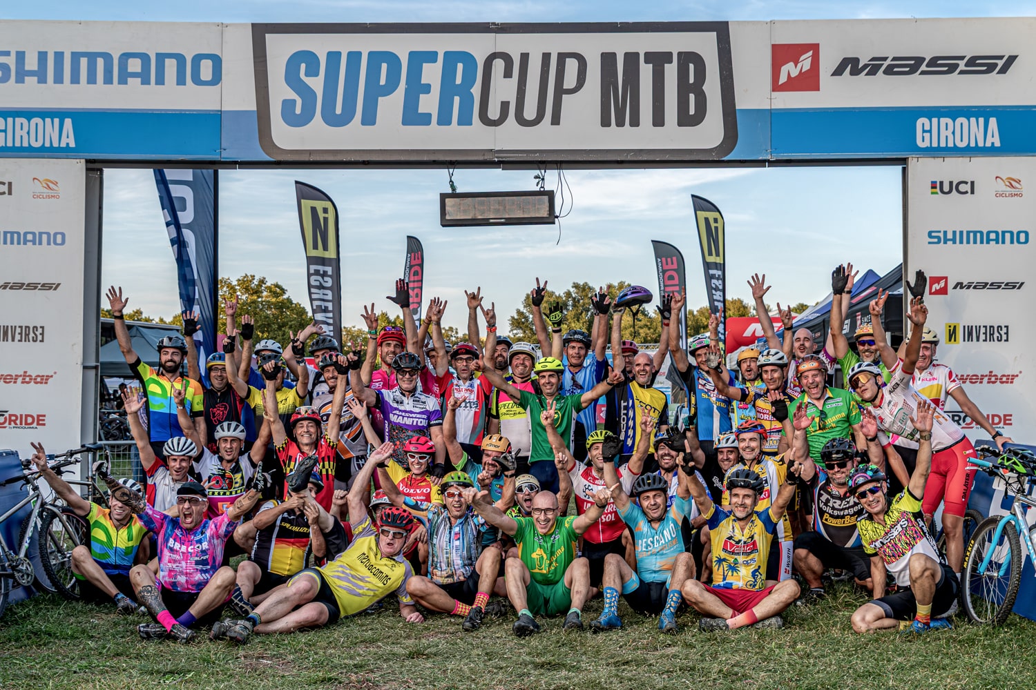Group of participants in the Sea Otter Europe MTB Classic sporting event celebrating the race under the starting arch