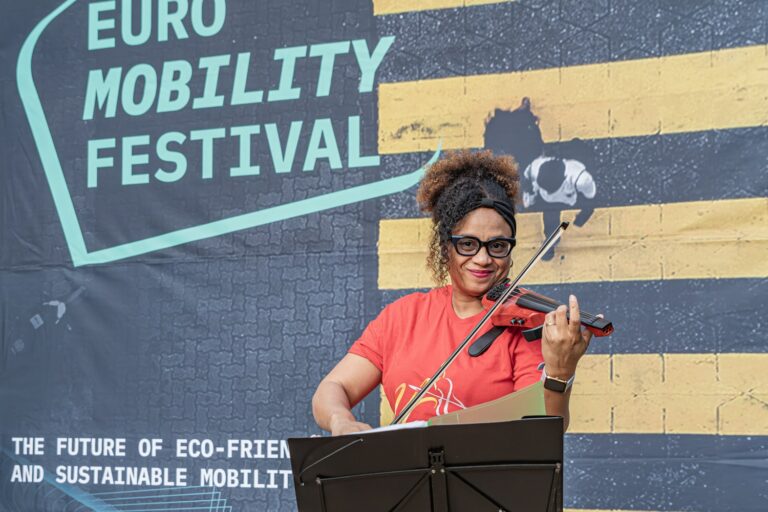 Mujer tocando el violín eléctrico para ambientar la zona de exposición en el festival internacional del ciclismo europeo, Sea Otter Europe