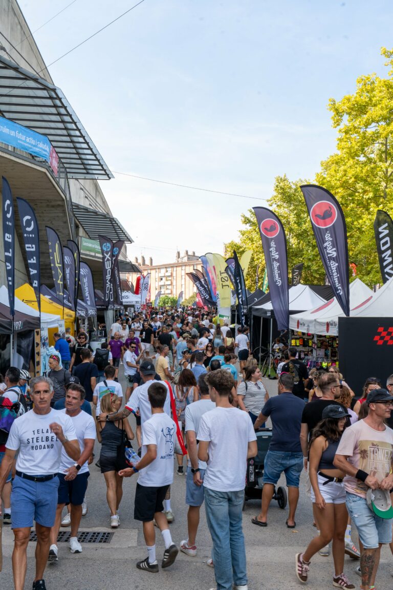 Visitantes paseando en la zona expo amarilla en el festival de ciclismo Sea Otter Europe, delante del pabellón municipal de Fontajau en Girona
